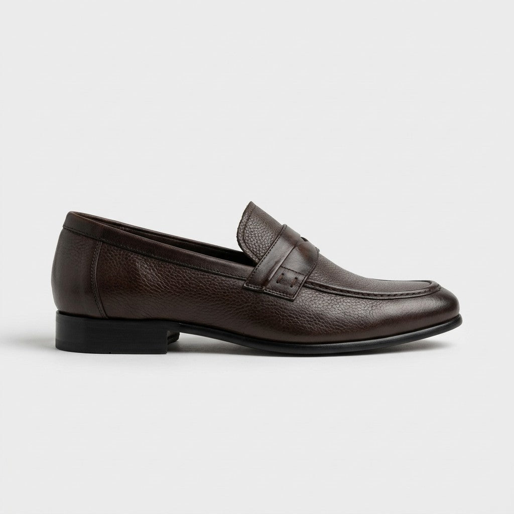 A dark brown pebbled leather penny loafer shown in a side profile view against a light gray background.