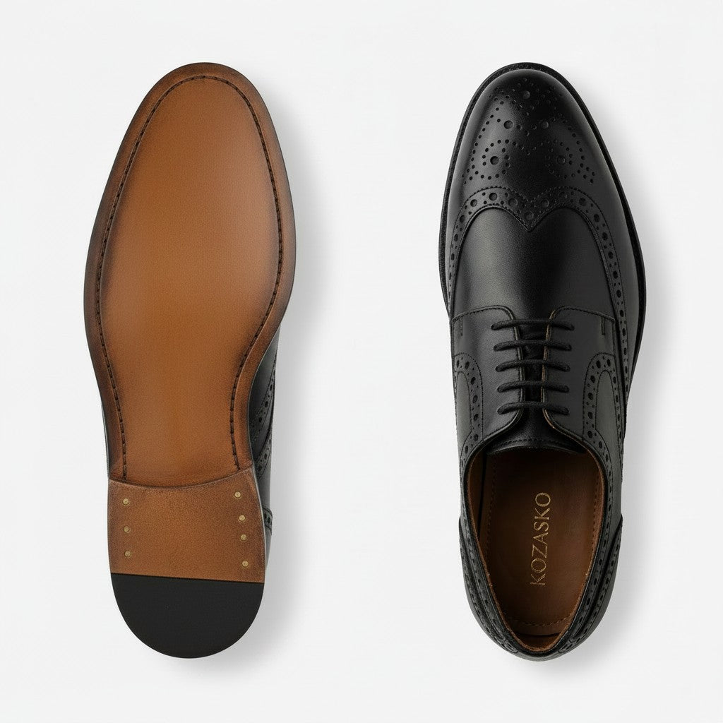 A pair of men's wingtip oxford shoes shown from the top on a light gray background, displaying both the black brogue leather upper and the brown leather sole.