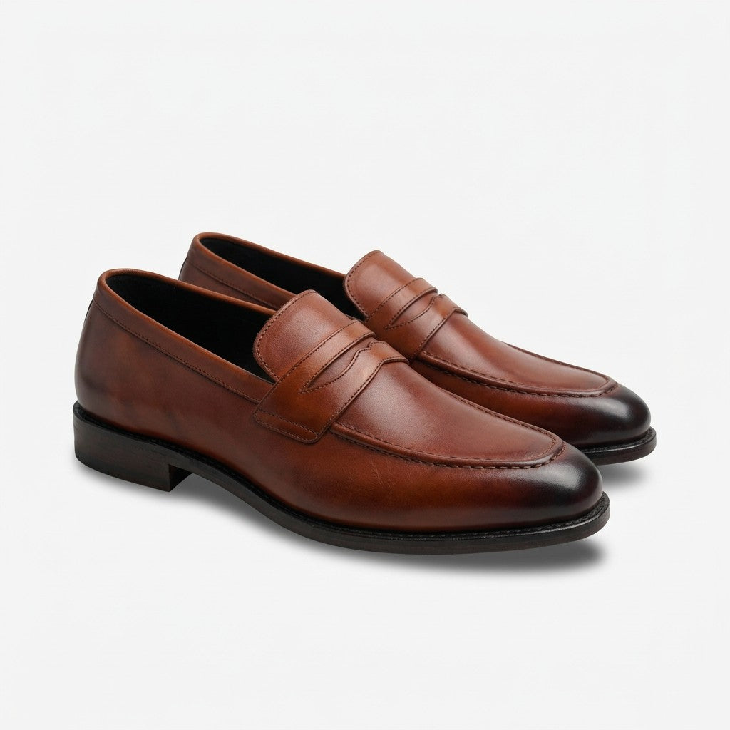 A pair of classic brown leather penny loafers with a smooth finish and dark contrast stitching, displayed on a clean white background.
