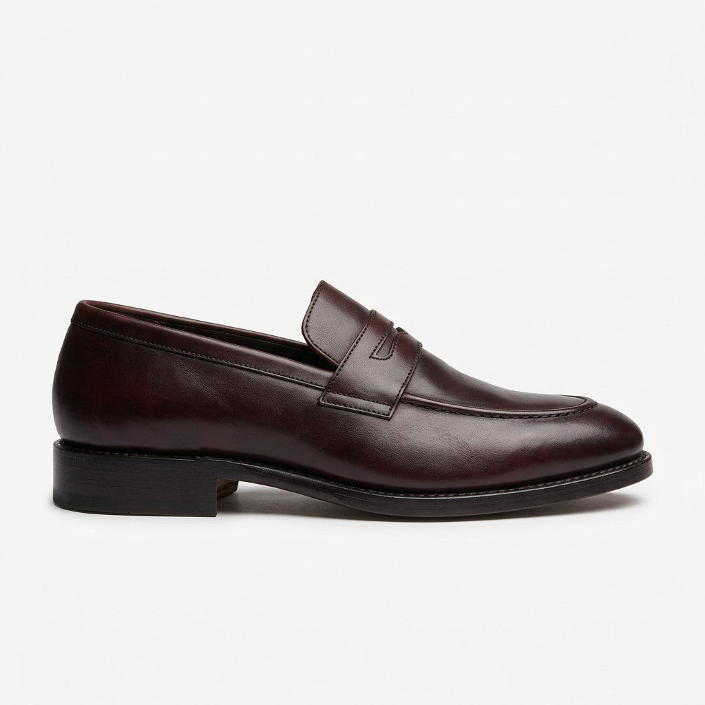 A dark brown leather penny loafer shoe shown from a side profile view against a clean white background.