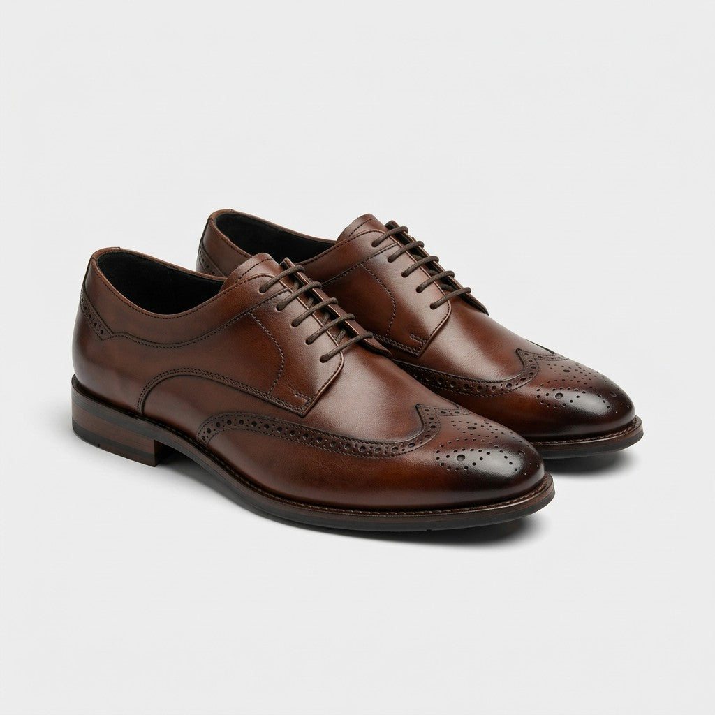A pair of men's brown leather wingtip oxford shoes with decorative brogue detailing and laces, displayed on a clean light gray background.