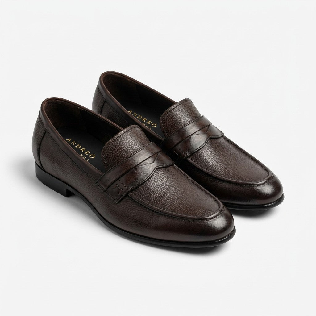 A pair of dark brown leather penny loafers with a pebbled texture, shown from a three-quarters angle on a light gray background. The brand name 'ANDREA D'ORSO' is visible in gold lettering on the inner sole of the left shoe.