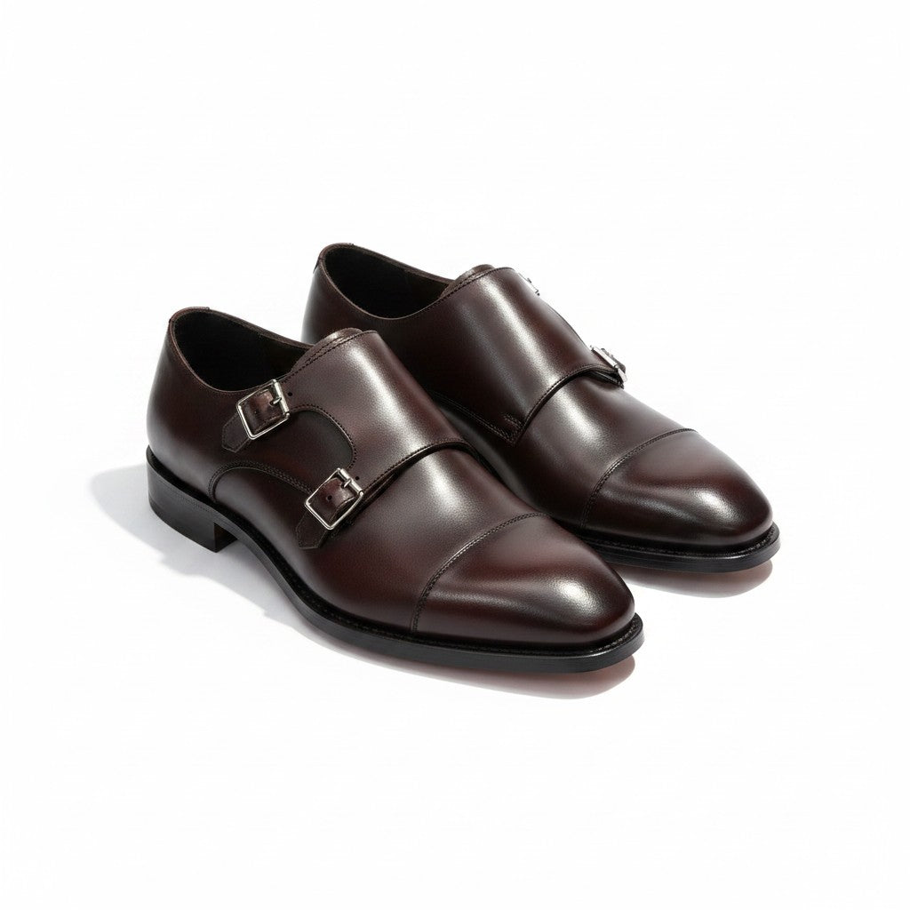 A pair of dark brown leather double monk shoes with silver-tone buckle straps, shown on a clean white background.