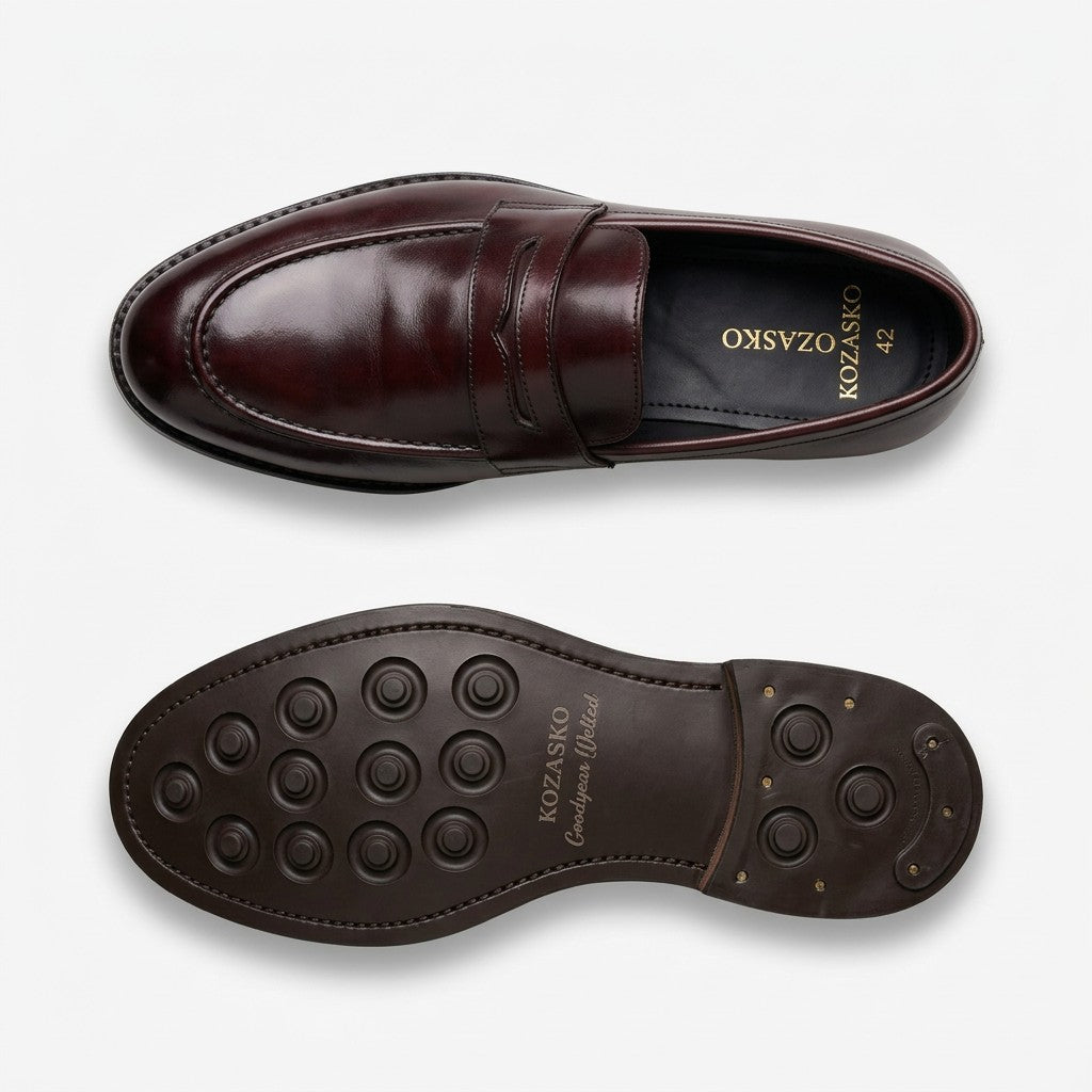 A pair of dark brown leather penny loafers shown from the top and bottom on a light gray background. The top view shows the polished leather upper with a penny strap, while the bottom view shows the dark brown textured rubber outsole with the brand name 'KOZASKO' printed on it.